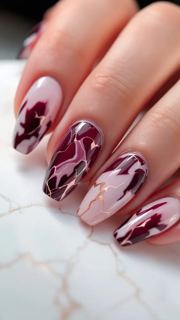 A close-up of nails featuring a marble effect design with wine undertones, pink, white, and gold accents.