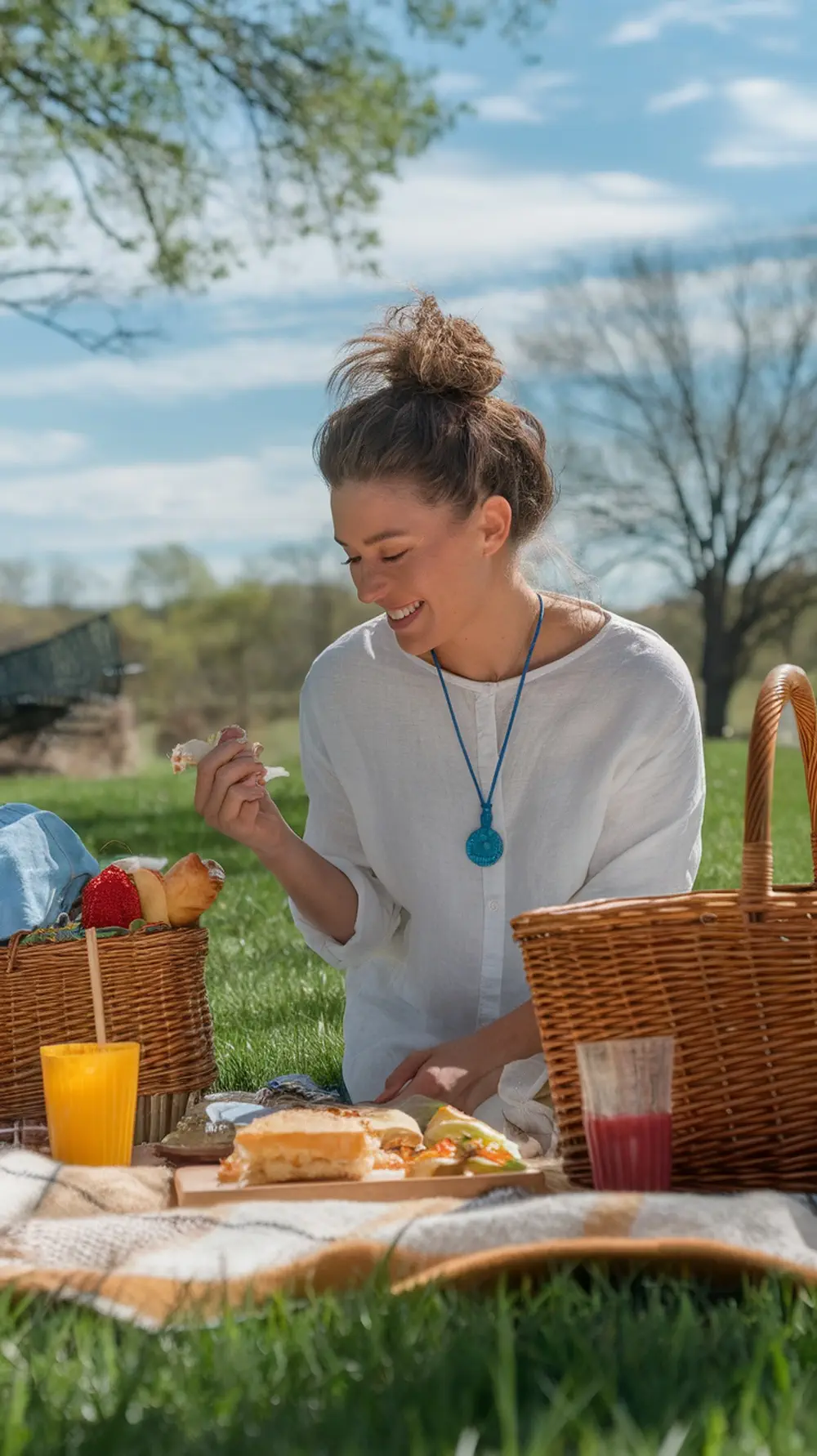 A woman enjoying a summer picnic with a messy bun hairstyle.