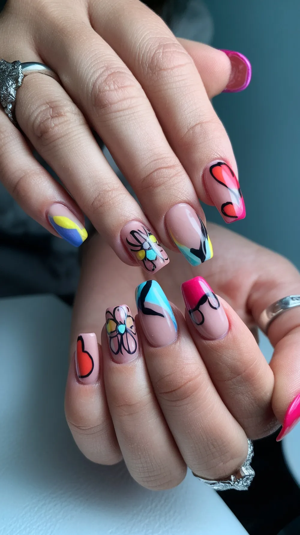 Colorful nail art featuring floral designs and abstract patterns on long nails.